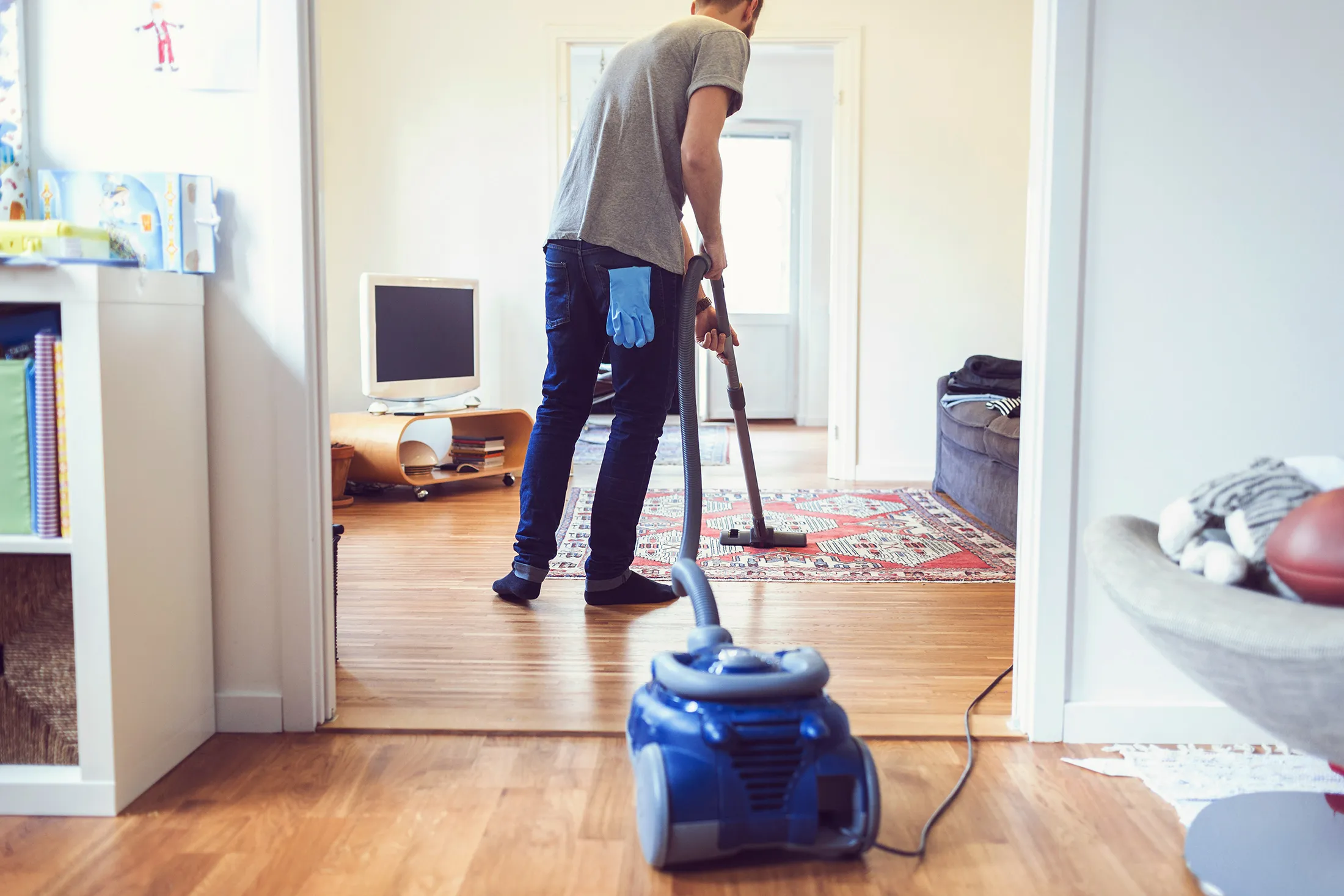 Rear view of man vacuuming carpet
