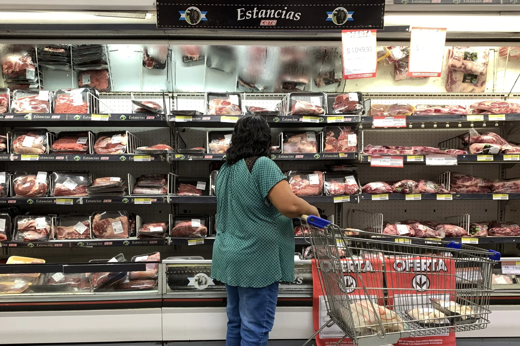 A customer looks at the prices of meat at a supermarket in Buenos Aires.