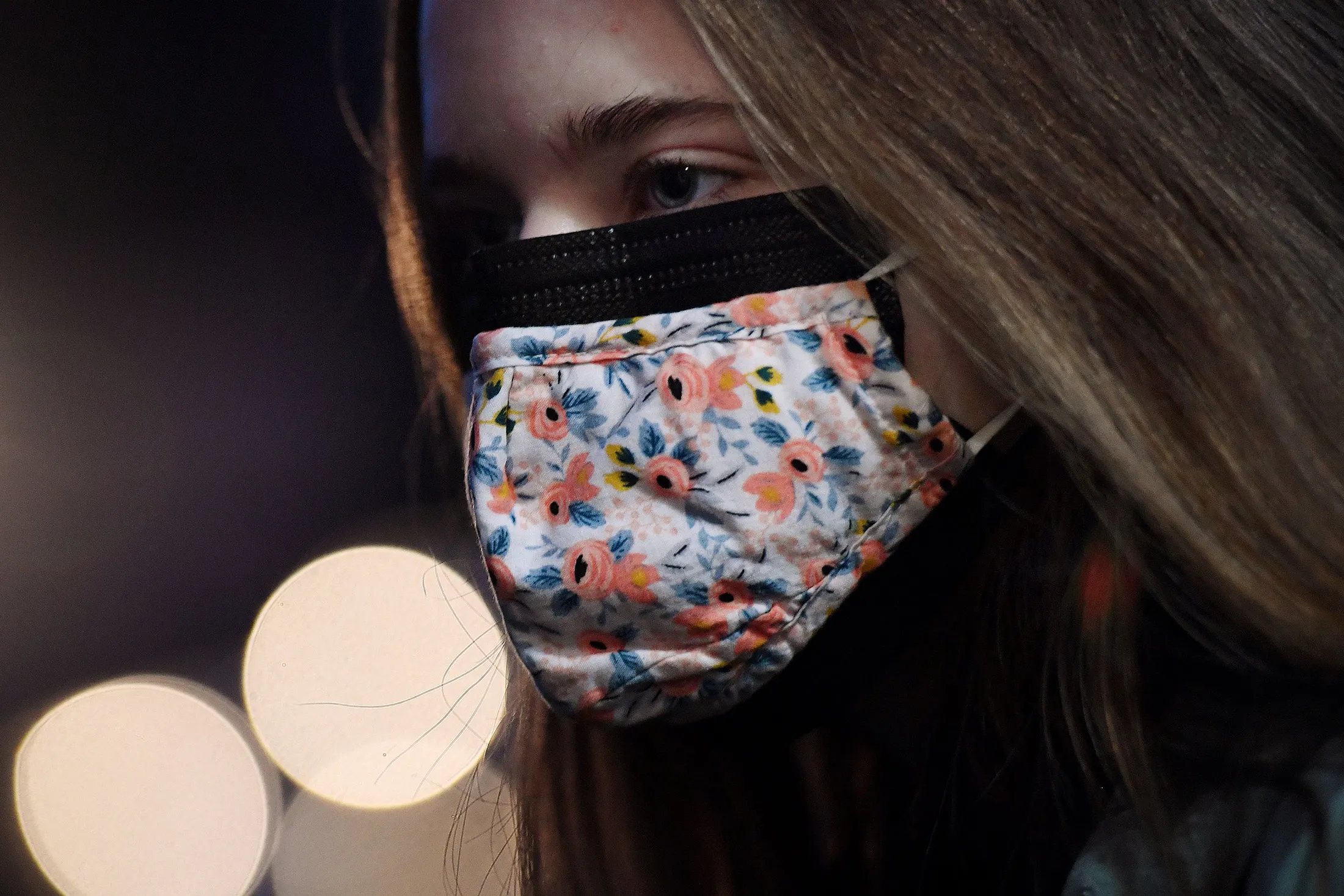 This illustration shows a woman wearing two facemasks, a cloth mask over a surgical mask.