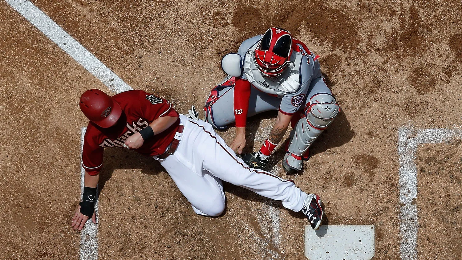Chris Owings #16 of the Arizona Diamondbacks safely slides in to score a run past catcher Jose Lobaton #59 of the Washington Nationals during the second inning of a game at Chase Field on May 13, 2015, in Phoenix.
