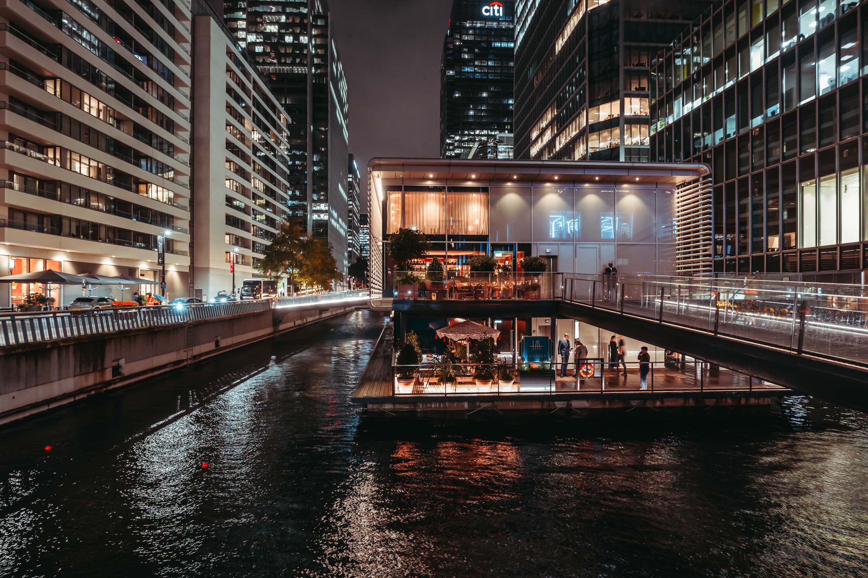 A restaurant built on a floating barge in Canary Wharf, illuminated at nighttime.