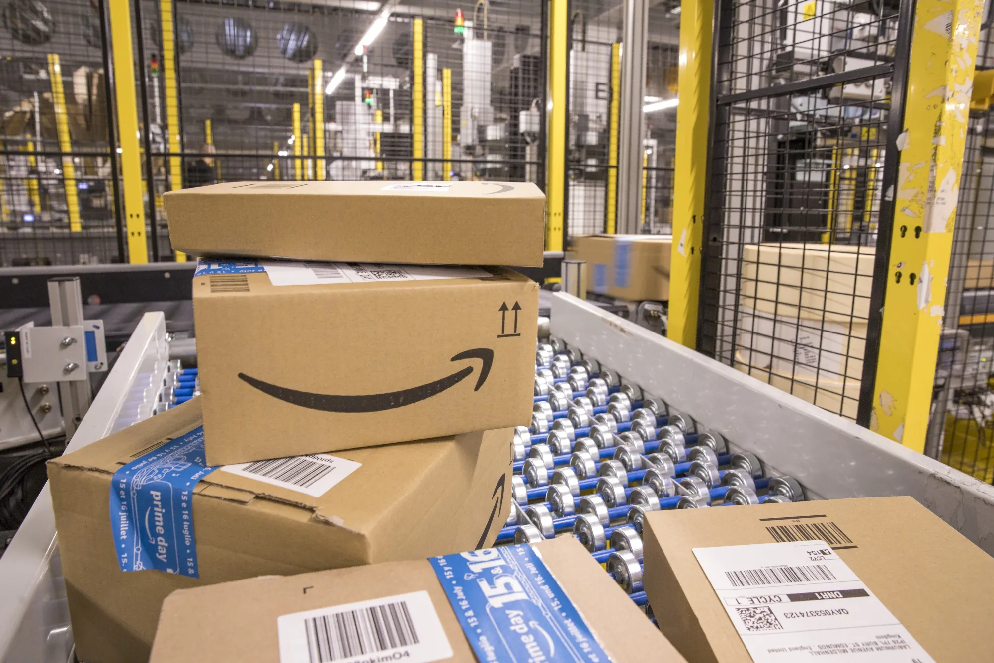 Packed boxes pass along a conveyor belt at the Amazon.com Inc. fulfilment centre in Tilbury, U.K. on Friday, July 12, 2019. By offering 12 extra hours of deals during this year's Prime Day, Amazon will pull in nearly 50% more in sales, according to an estimate from Coresight Research.