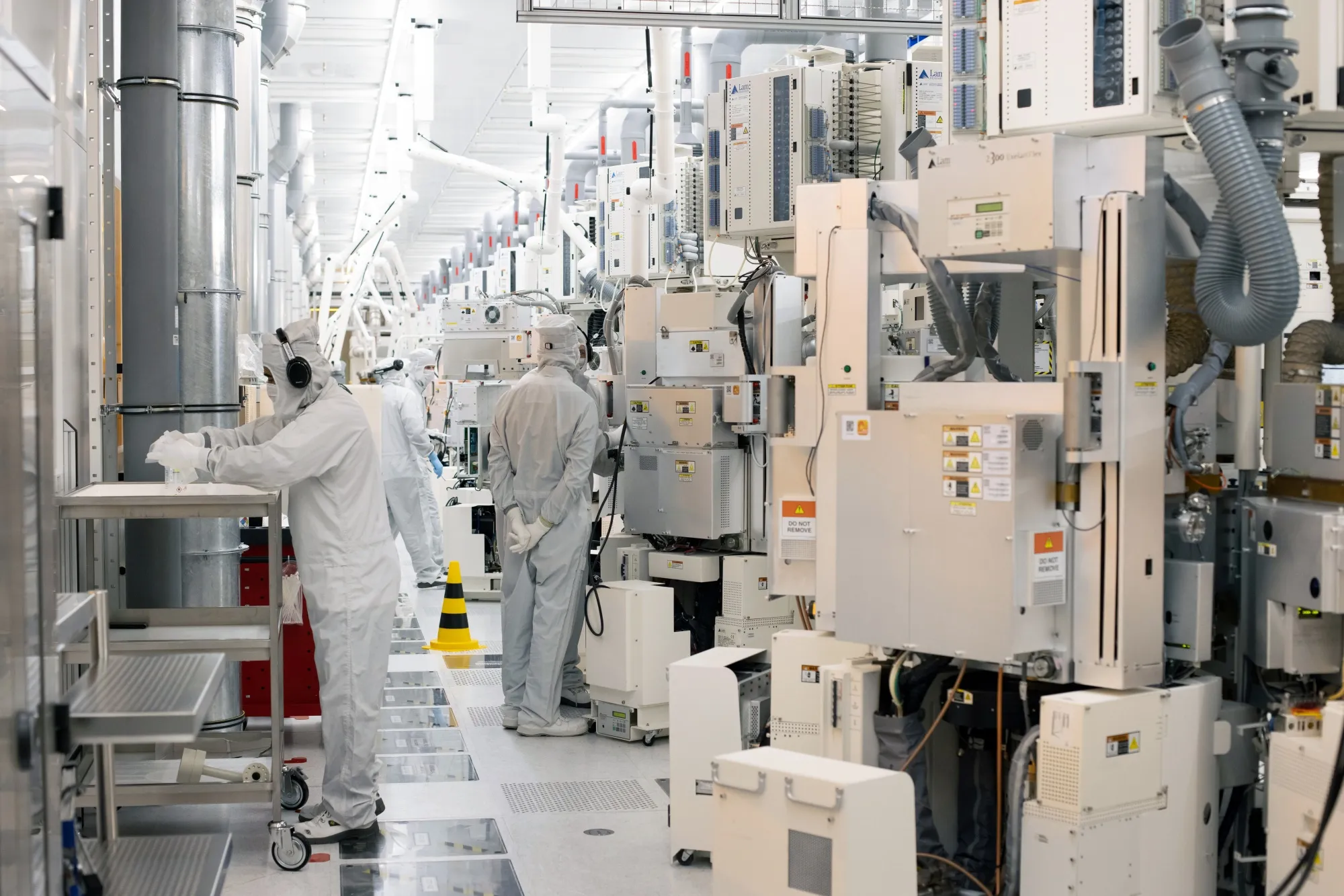 Technicians perform production control tasks in a cleanroom at a semiconductor fabrication plant in Dresden, Germany.