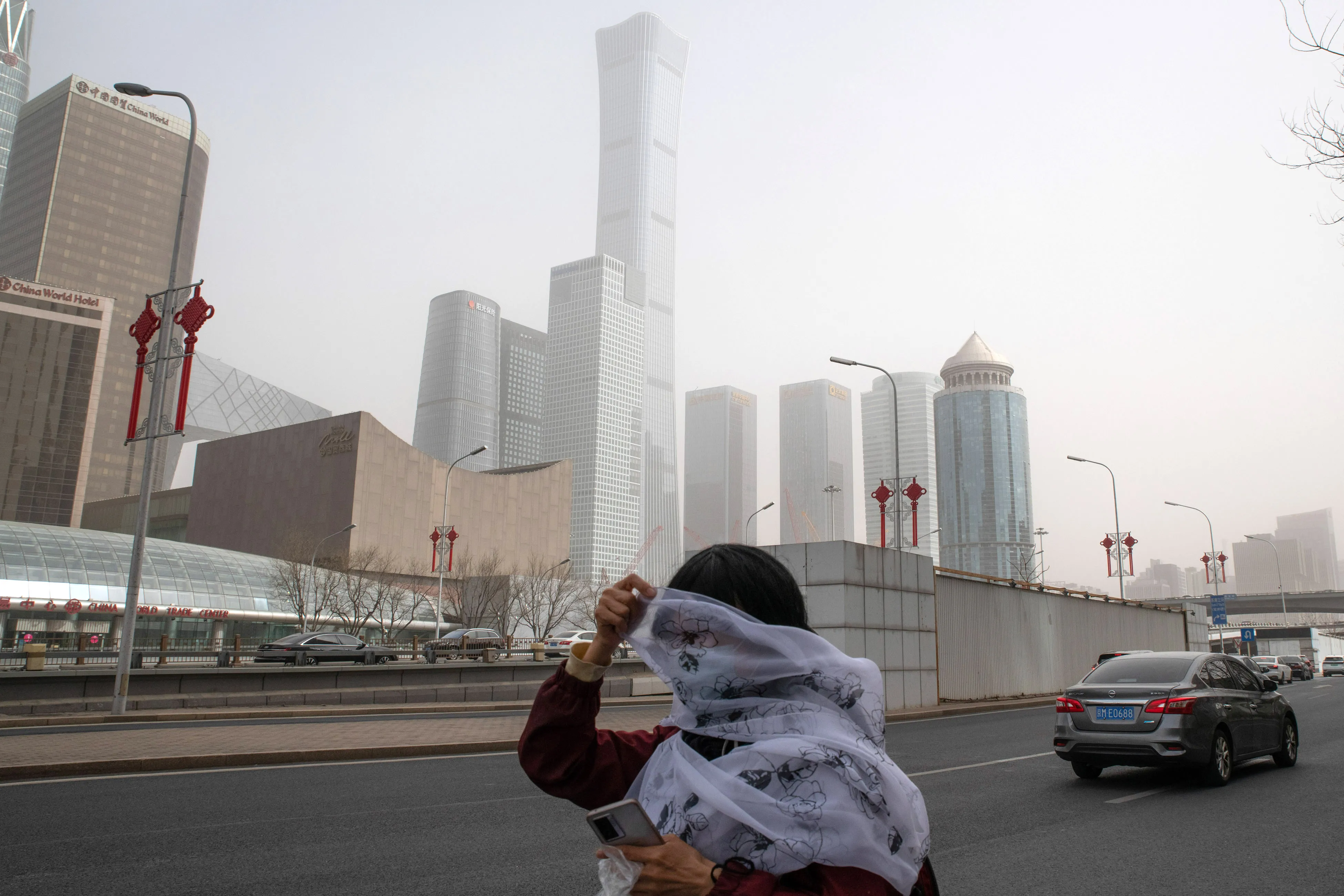 A pedestrian covers her face with a scarf while walking along a road shrouded in smog in Beijing.&nbsp;