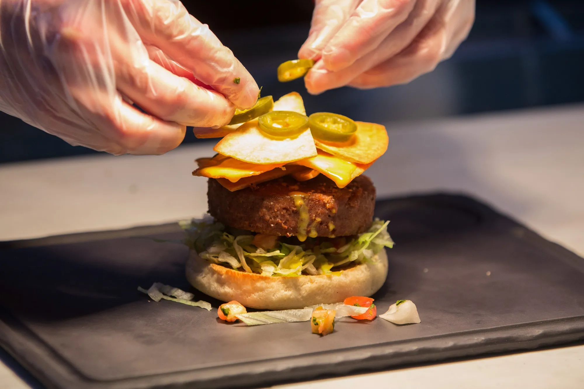 A chef garnishes a burger, made with a Beyond Meat plant-based burger patty.