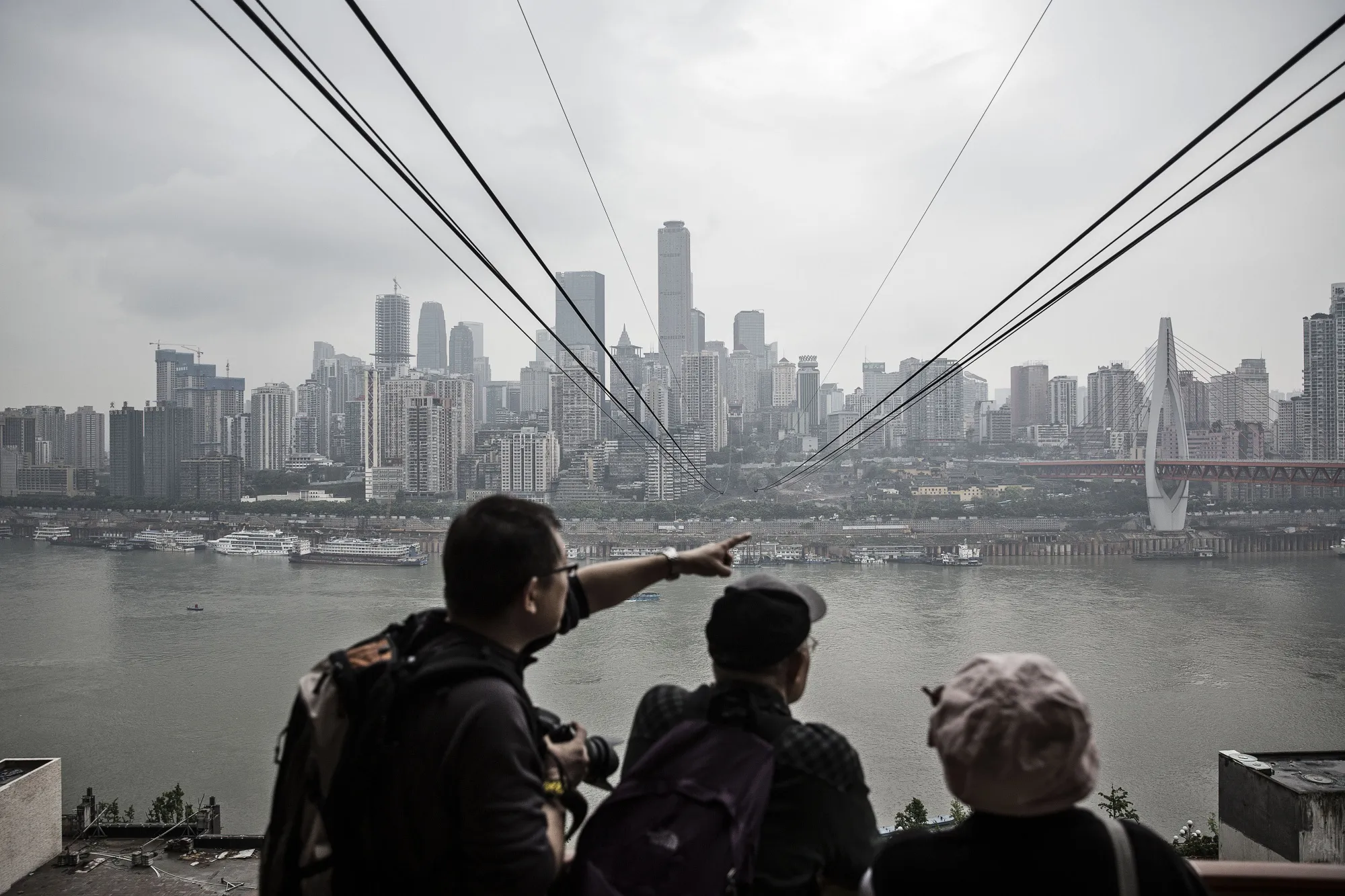 Passengers looks out at the city skyline as they wait to board a cable car at a Yangtze River Cableway station in Chongqing, China.