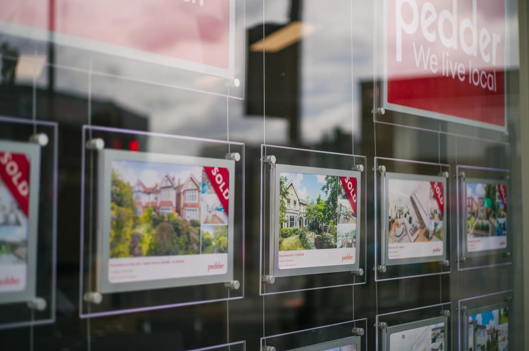 Listings of sold residential properties in the window of an estate agents in London.