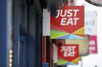 A Just Eat Plc sign hangs outside a takeaway restaurant in London, U.K.