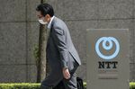 A pedestrian walks past a signage displayed outside the Nippon Telegraph and Telephone Corp. (NTT) headquarters in Tokyo, Japan,