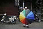 An umbrella seller walks along a road in the old quarter of Delhi.