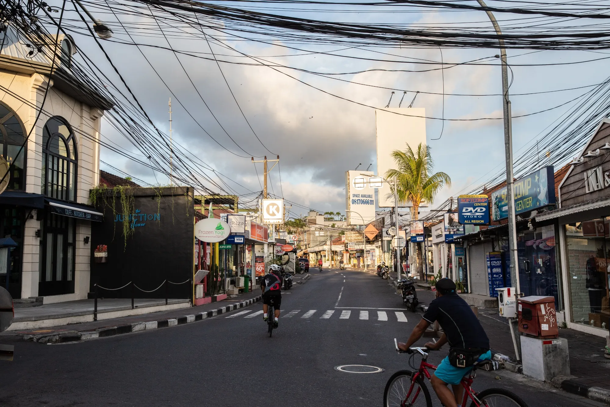 Cyclists ride past retail stores in Seminyak, Bali, Indonesia.