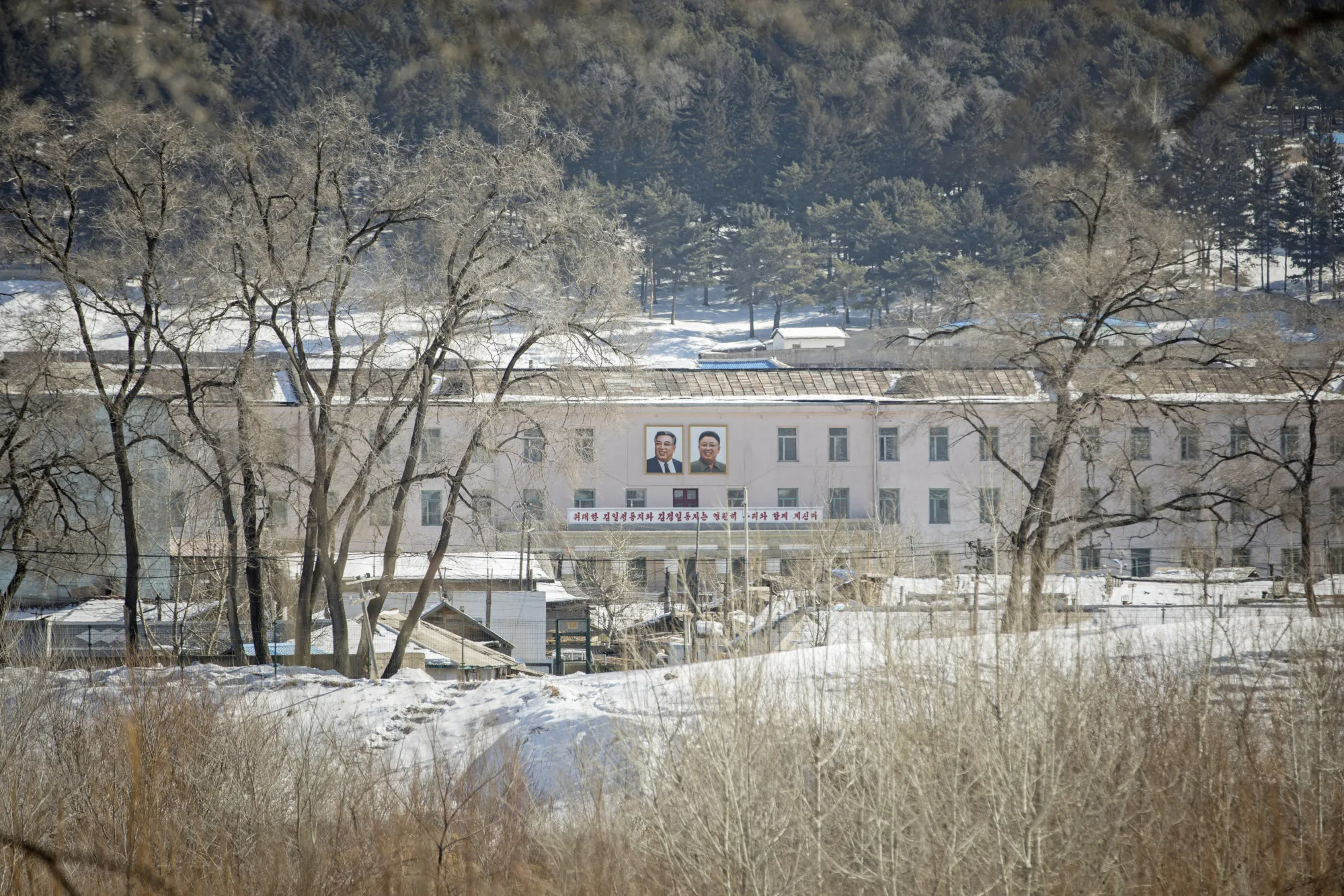 Portraits of former North Korean leaders Kim Il Sung, left, and Kim Jong Il are displayed on a building in Hyesan, North Korea, seen from across the border in Changbai, Jilin province, China.