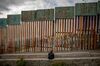 A person sits in front of a section of the U.S.-Mexico border wall in Tijuana, Mexico, on Saturday, May 19, 2018.