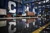 Trucks are reflected in a puddle as they wait in line to unload their containers onto CMA CGM SA's Benjamin Franklin container ship docked at the Guangzhou Nansha Container Port in Guangzhou, China, on Monday, Feb. 1, 2016. The Benjamin Franklin is the largest container ship ever to have docked at a U.S. port.