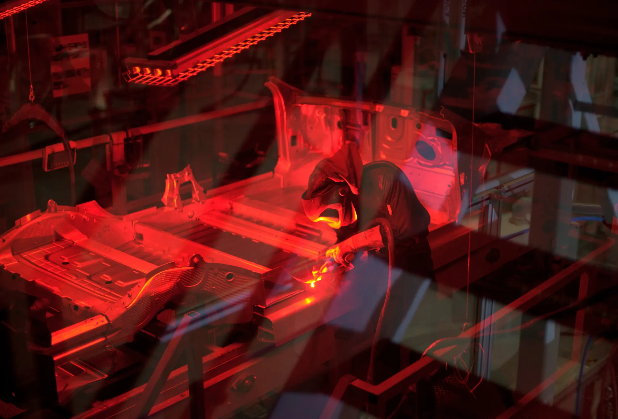A worker welds a Model S sedan chassis.