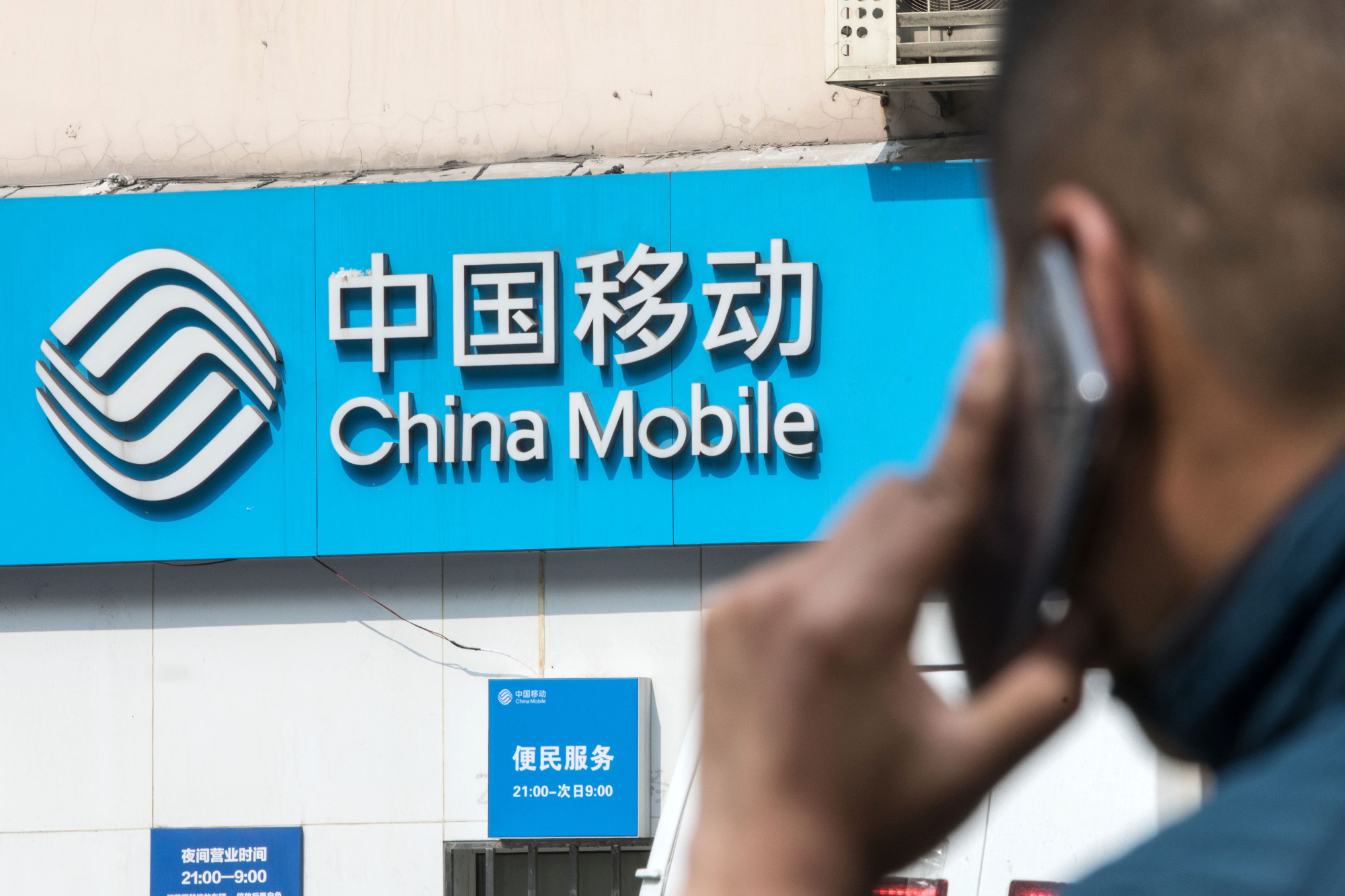 Signage for China Mobile Ltd. is displayed outside a store in Shanghai.