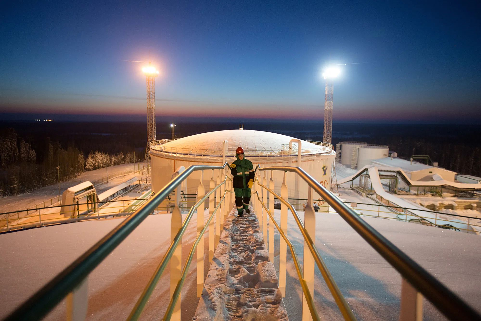 An employee walks across the top of an oil storage tank at night in the custody transfer facility at the Salym Petroleum Development oil fields near the Bazhenov shale formation in Salym, Russia, on Wednesday, Feb. 5, 2014. Salym Petroleum Development, the venture between Shell and Gazprom Neft, has started drilling the first of five horizontal wells over the next two years that will employ multi-fracturing technology, according to a statement today.