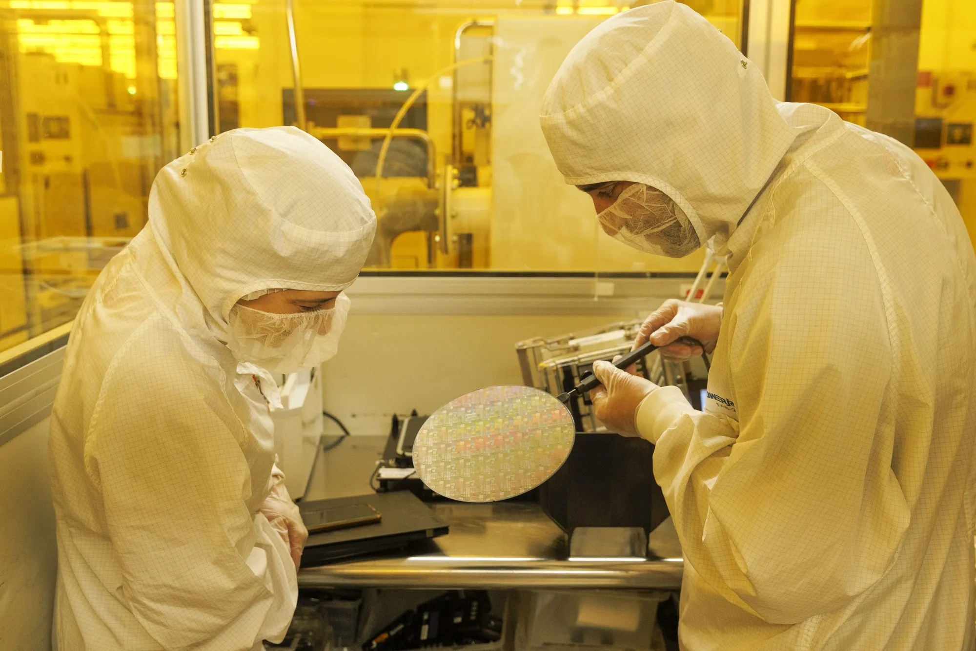 Technicians inspect a semiconductor wafer&nbsp;in the cleanroom at a semiconductor factory.