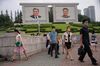 Pedestrians walk in central Pyongyang on August 19 with portraits of the late North Korean leaders Kim Il Sung and Kim Jong Il.