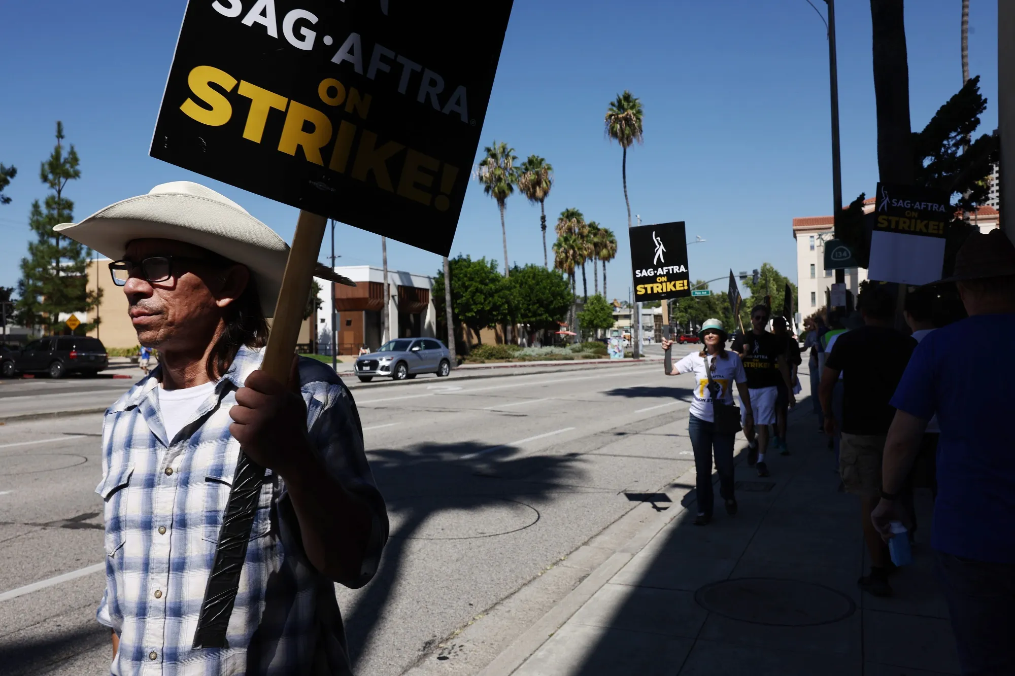 Striking SAG-AFTRA members picket outside Warner Bros. Studio.