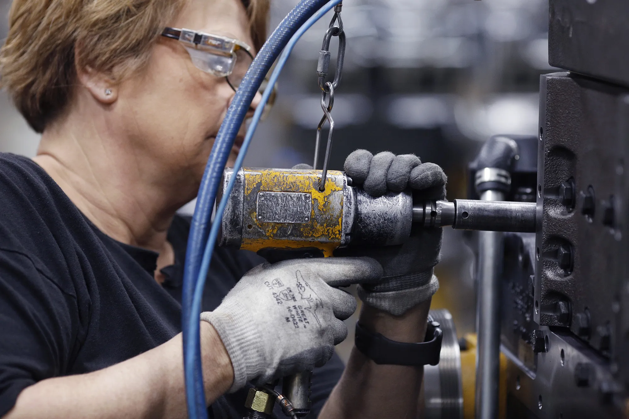 A factory worker uses a power drill to assemble components on a diesel engine in Seymour, Indiana.