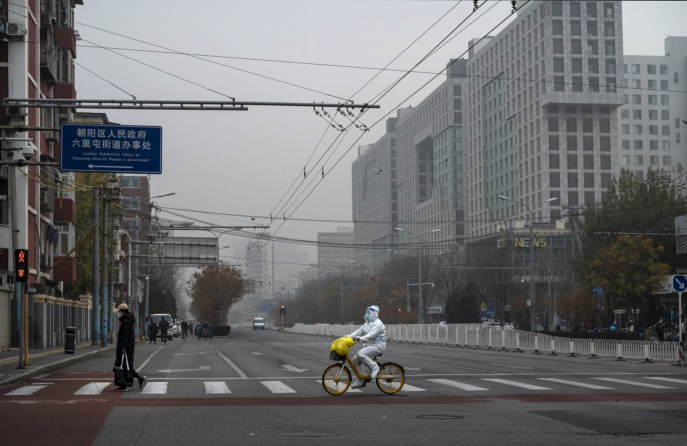 An epidemic control worker rides a bike across a nearly empty street near the Beijing’s Central Business District on Nov. 24. 