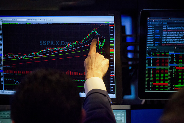 A trader points to monitor displaying an S&P 500 Index chart on the floor of the New York Stock Exchange.