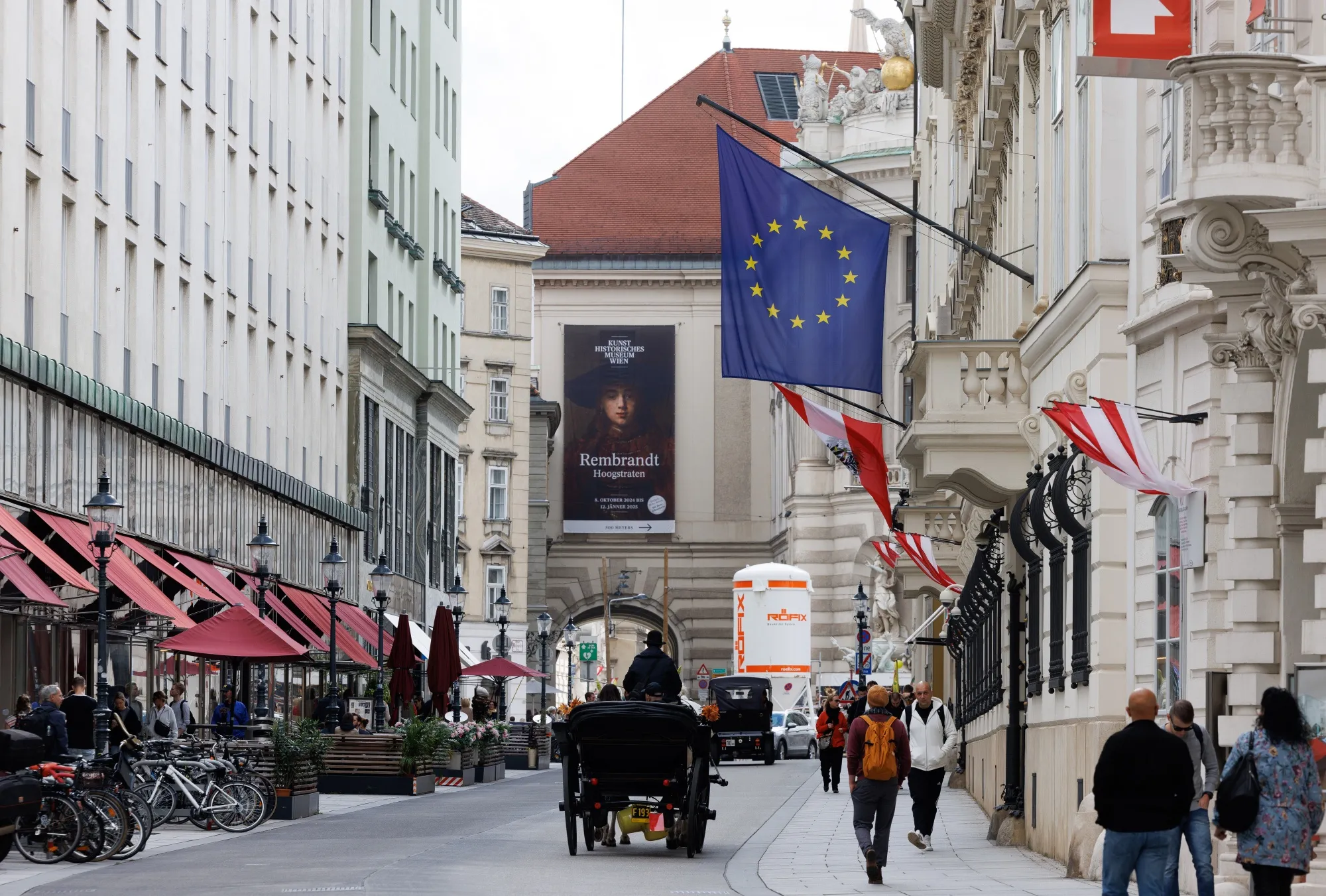 Tourists ride a horse-drawn carriage past a European Union flag in Vienna, Austria.