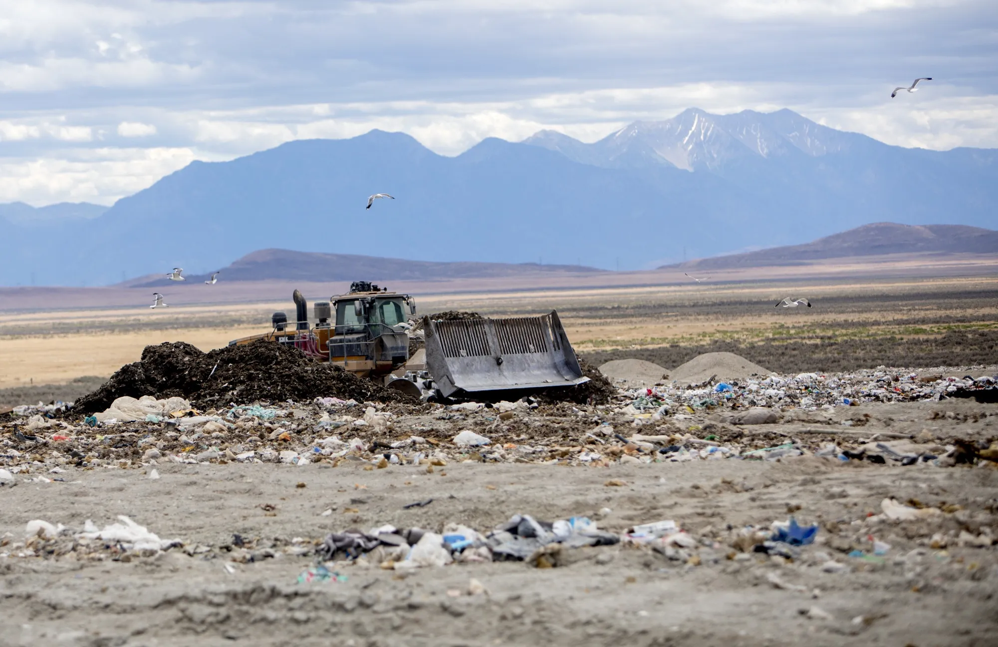 A bulldozer moves trash at a landfill refuse site.