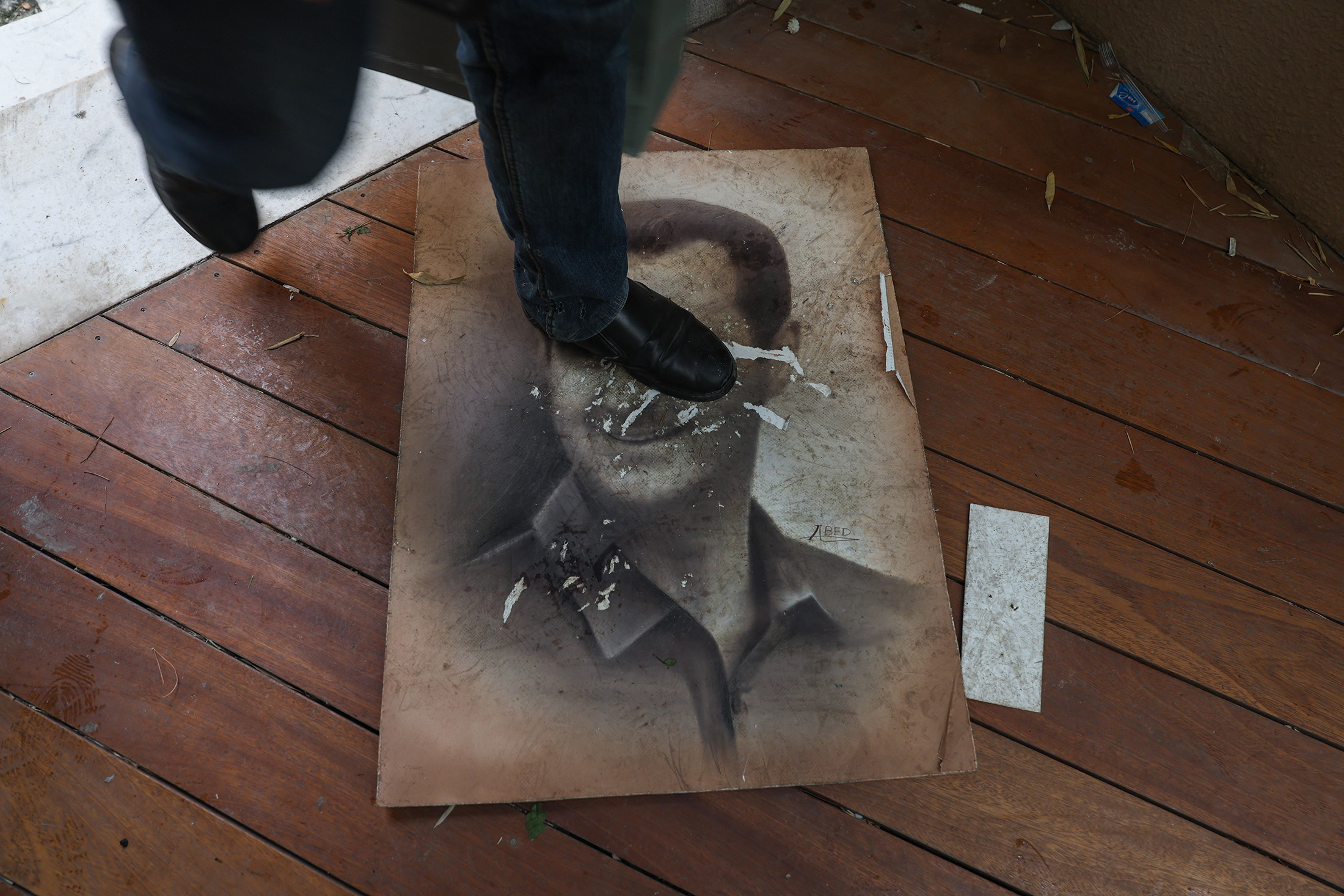 A man treads on a picture of Syria's ousted president Bashar al-Assad as people enter his residence in Damascus' Malki area on Dec.&nbsp;8.