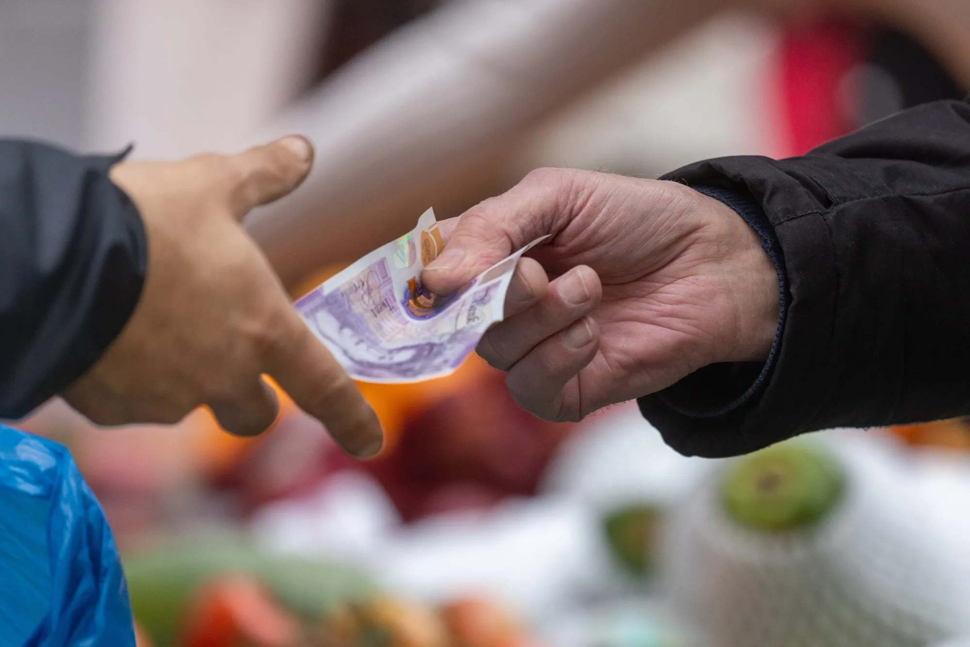 A customer hands over a 20 pound banknote at a fruit and vegetable stall in Bexleyheath, Greater London, UK.