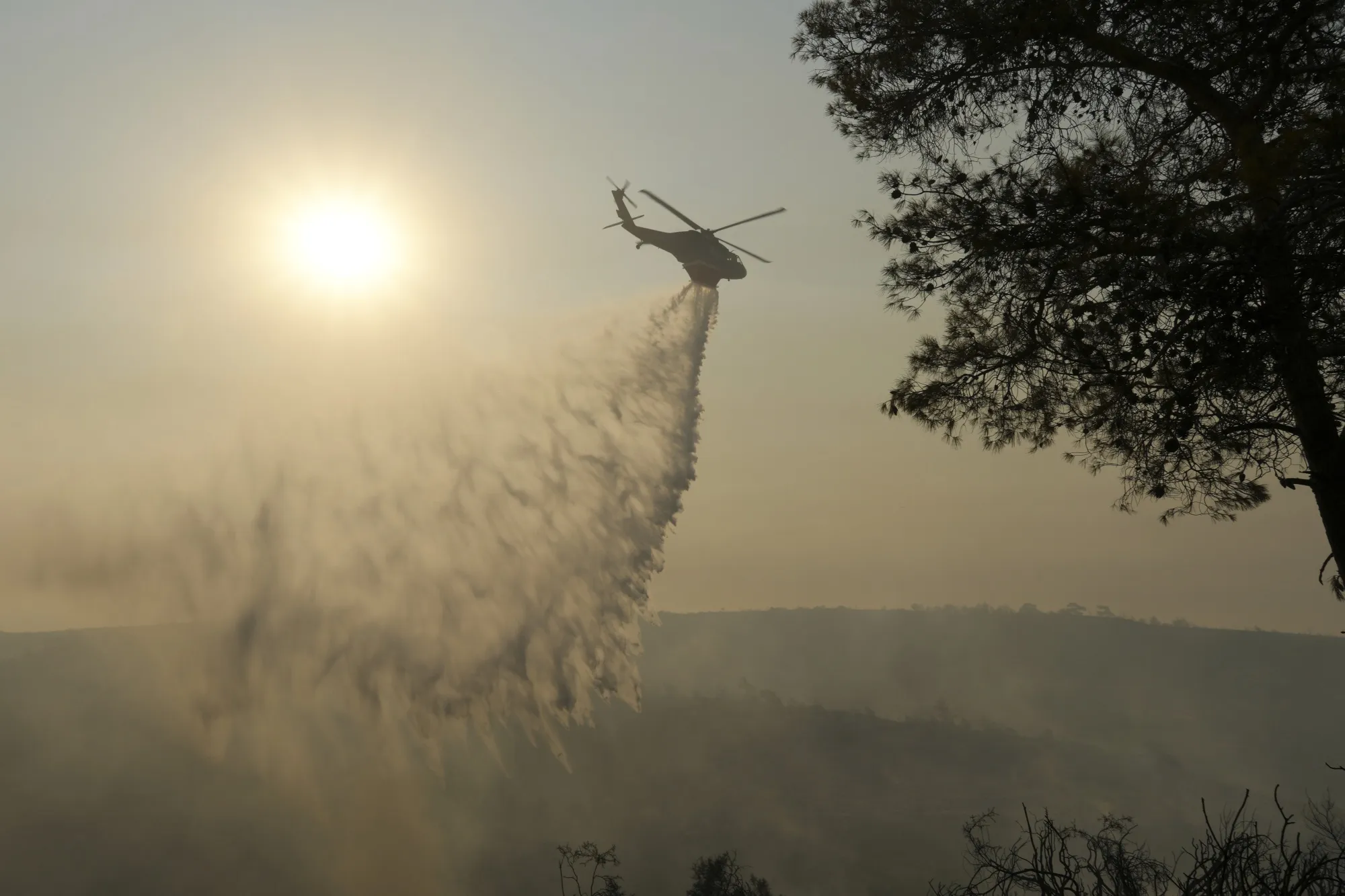 A helicopter drops water over a burned forest in Souni village, Cyprus, during a wildfire,&nbsp; on July 24.
