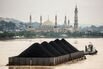 A tug pulls a coal barge past the Islamic centre on August 26, 2016 in Samarinda, Kalimantan, Indonesia.
