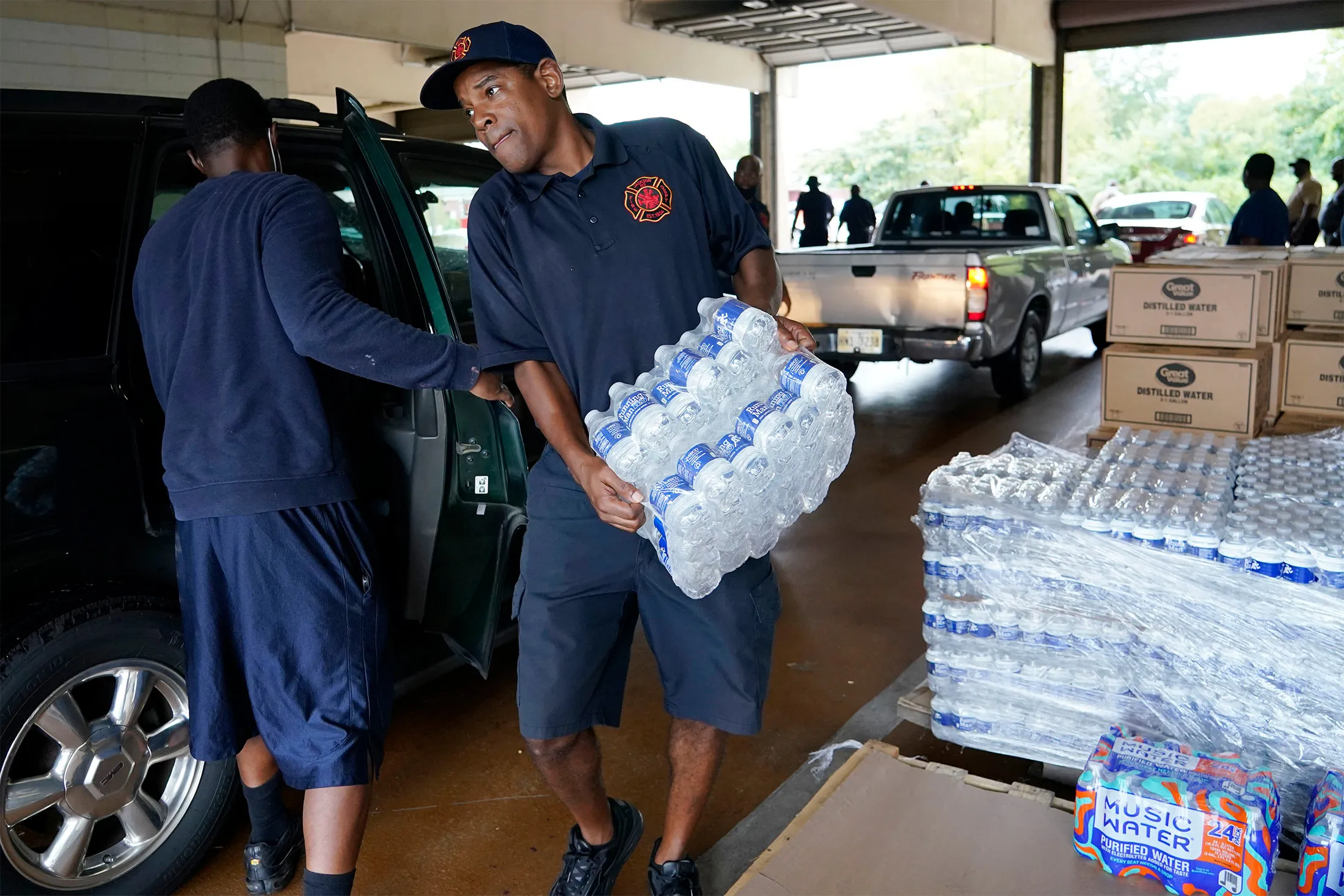 A&nbsp;firefighter loads cases of bottled water into a resident's vehicle in Jackson, Miss., on&nbsp;Aug. 18.