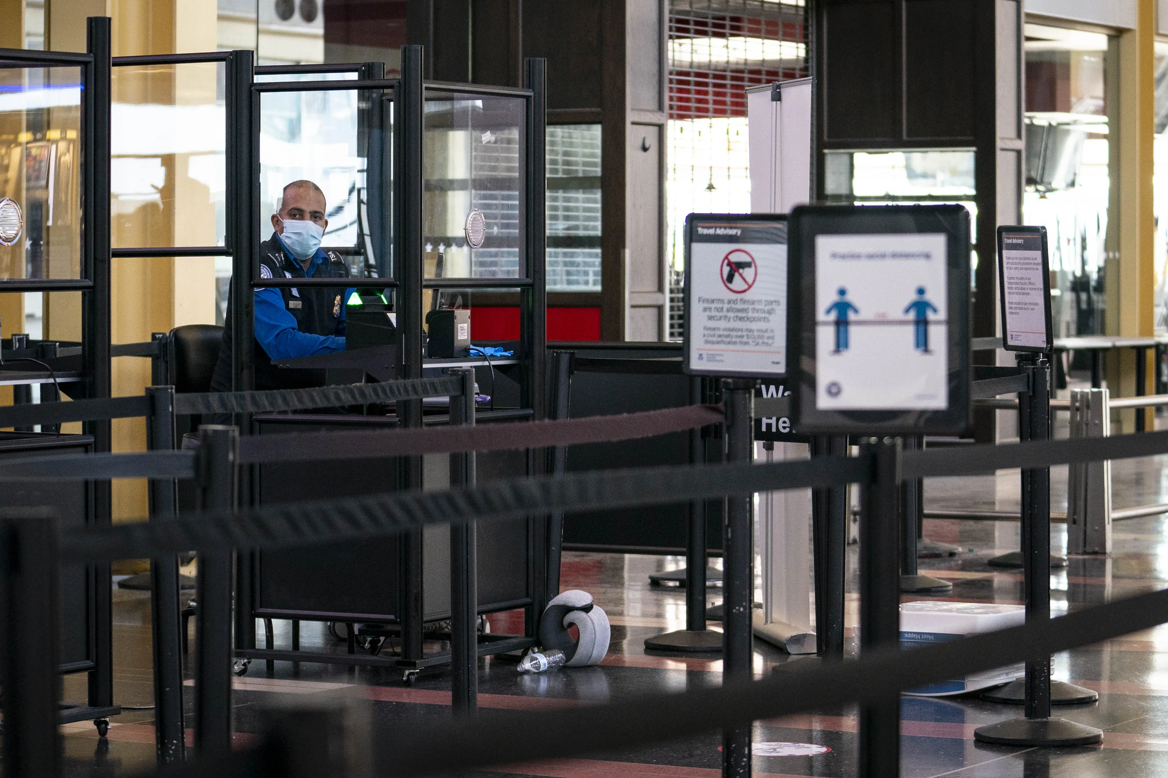 &nbsp;A Transportation Security Administration&nbsp;agent wears a protective mask behind a barrier at Ronald Reagan National Airport in Arlington, Virginia