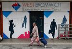 A shopper walks past a boarded shop in West Bromwich, U.K.