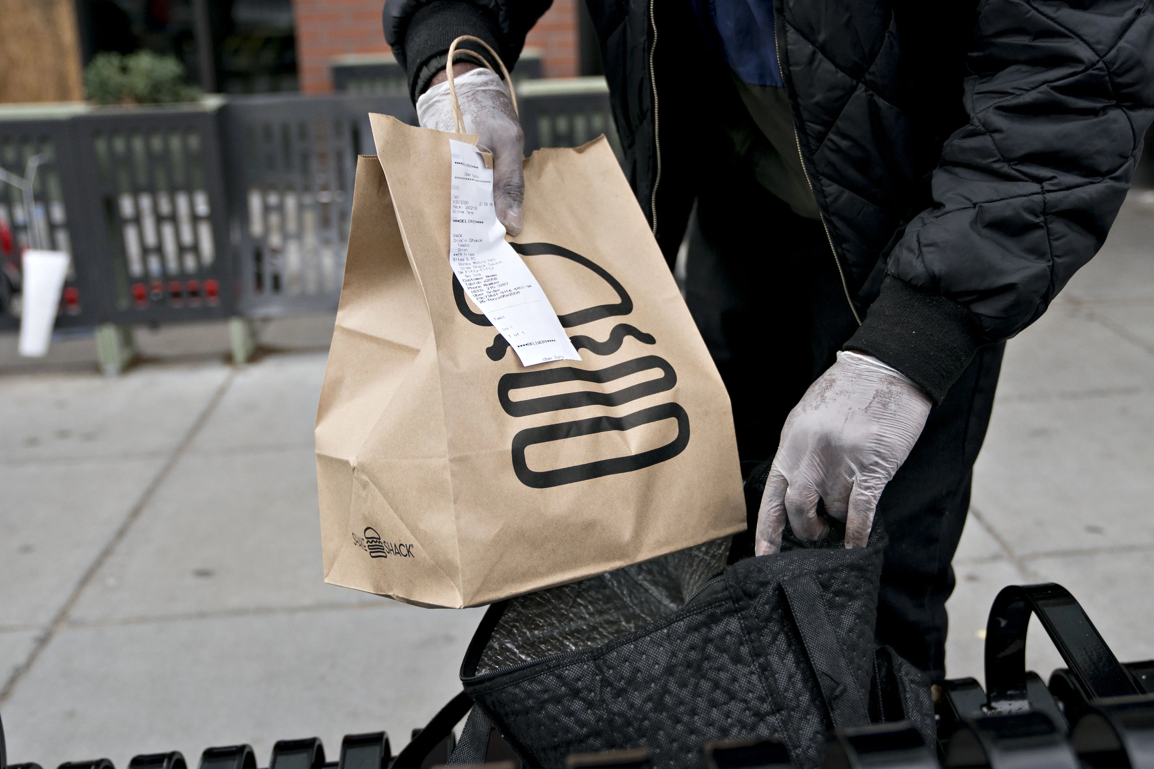 A&nbsp;delivery person places a Shake Shack take-out order into an insulated bag outside the restaurant in Washington, D.C., U.S., on&nbsp;April 20.