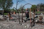 A woman walks through her damaged property&nbsp;in Sloboda-Kukharivska, Ukraine on May 10.&nbsp;