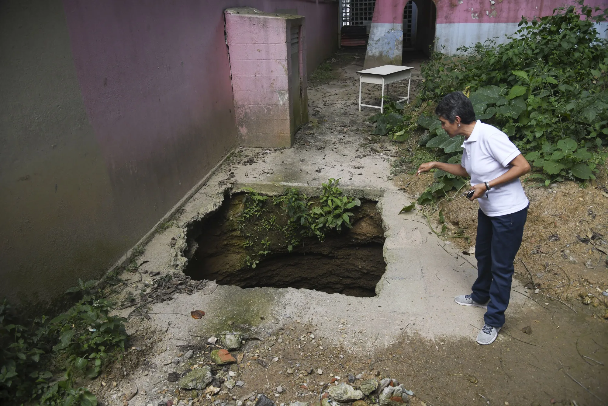 Elementary teacher Nayibe Moreno stares down at an exposed sewage pipe in the Cecilio Acosta school’s kindergarten area.
