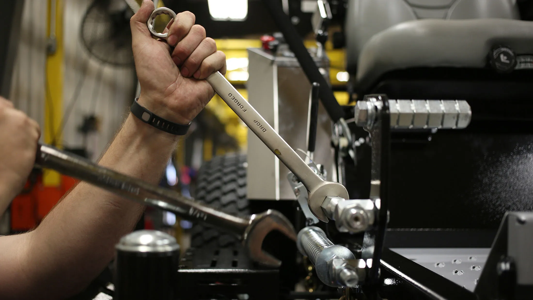A worker tightens a bolt on a completed lawnmower at a manufacturing facility in Coatesville, Indiana.
