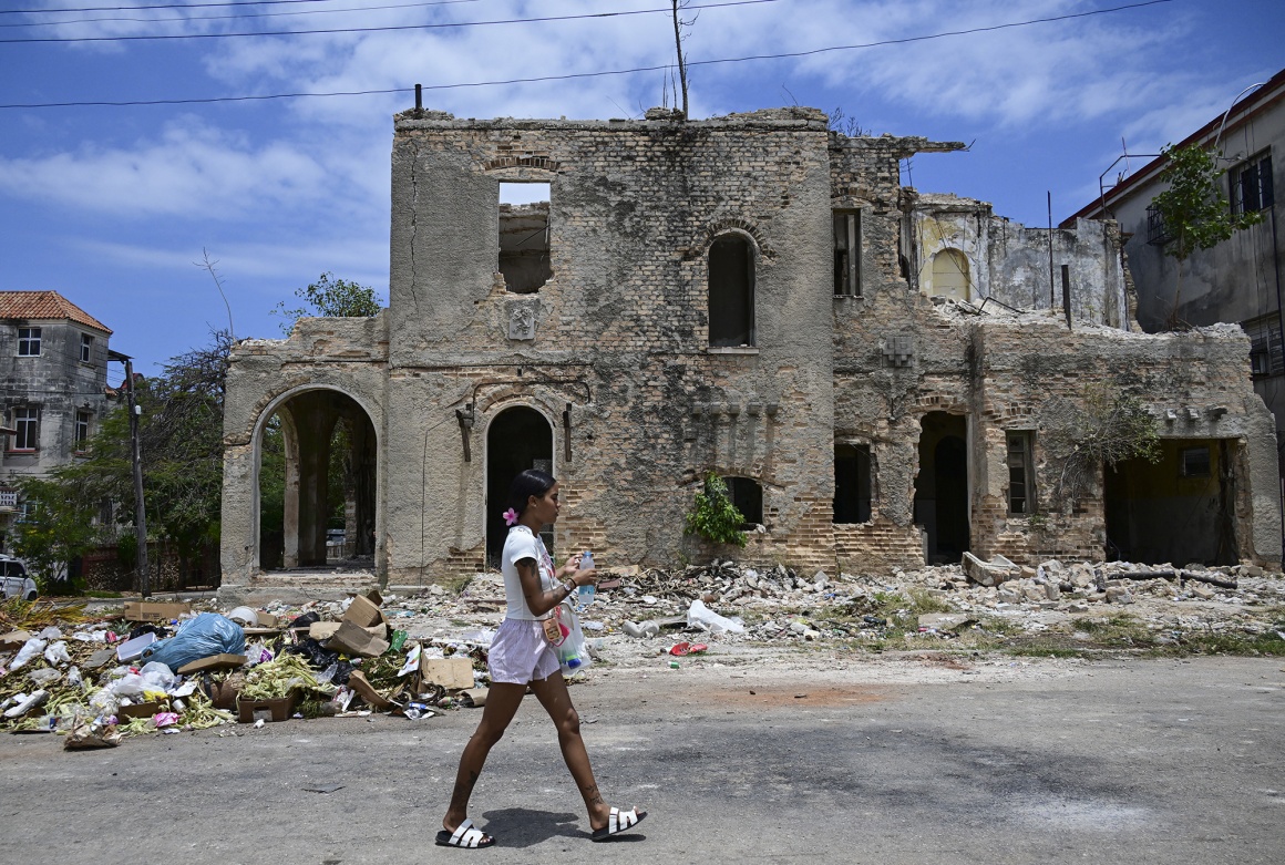 A woman walks in front of a house under renovation in a neighborhood of Havana.