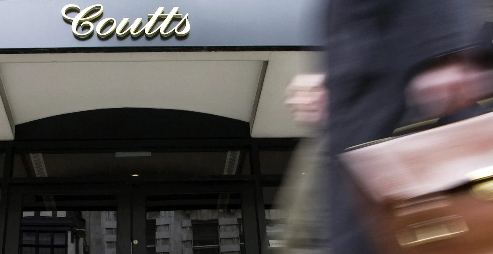 Pedestrians walk past a branch of Coutts & Co.