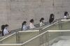 Morning commuters wearing protective masks ride on an escalator at a plaza in downtown Guangzhou, China, on Wednesday, May 13, 2020. 