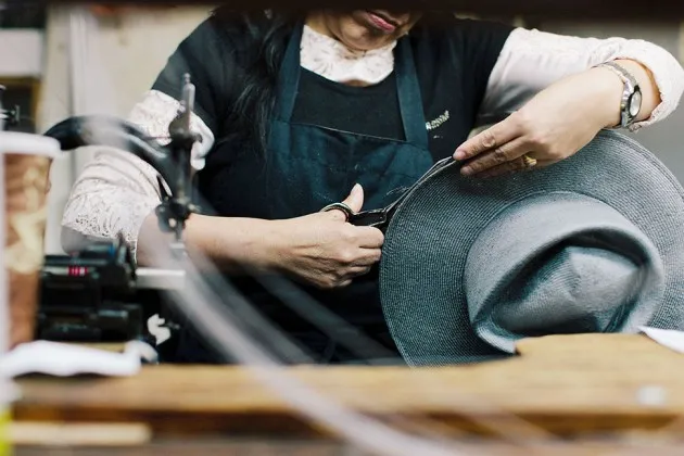 Trimming fabric from a hat at the Satya Twena Studio manufacturing facility in New York