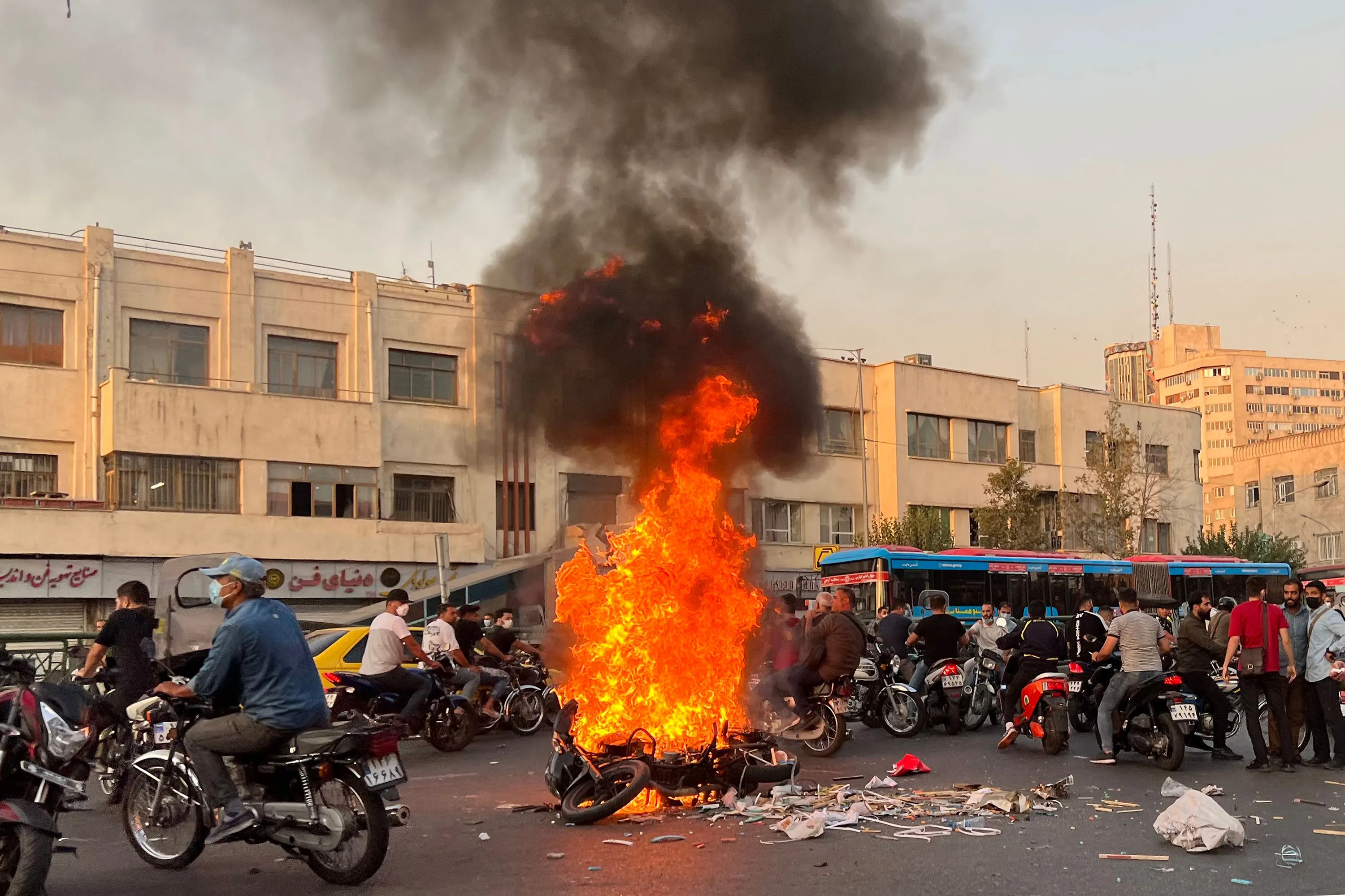 People gather&nbsp;next to a burning motorcycle in Tehran on Oct.&nbsp;8, 2022.&nbsp;