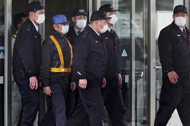 Ghosn, second from left, is escorted by authorities from a Tokyo Detention House on Mar. 6, 2019.
