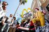 Robert Wideman, a maintenance mechanic at McDonalds, shines the shoes of a Ronald McDonald statue outside of a restaurant while protesting with fast-food workers and supporters in Los Angeles, on Aug. 29