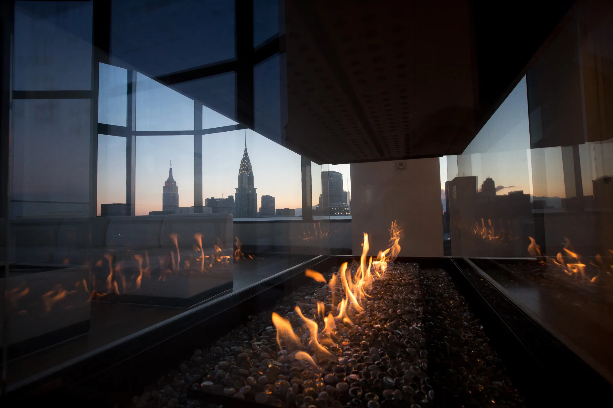The Empire State and Chrysler buildings are seen through a fireplace in the penthouse apartment at the 50 United Nations Plaza building in New York, U.S., on Tuesday, June 7, 2016. About 3,574 newly built apartments will reach the market in 2016, according to brokerage Corcoran Sunshine Marketing Group.