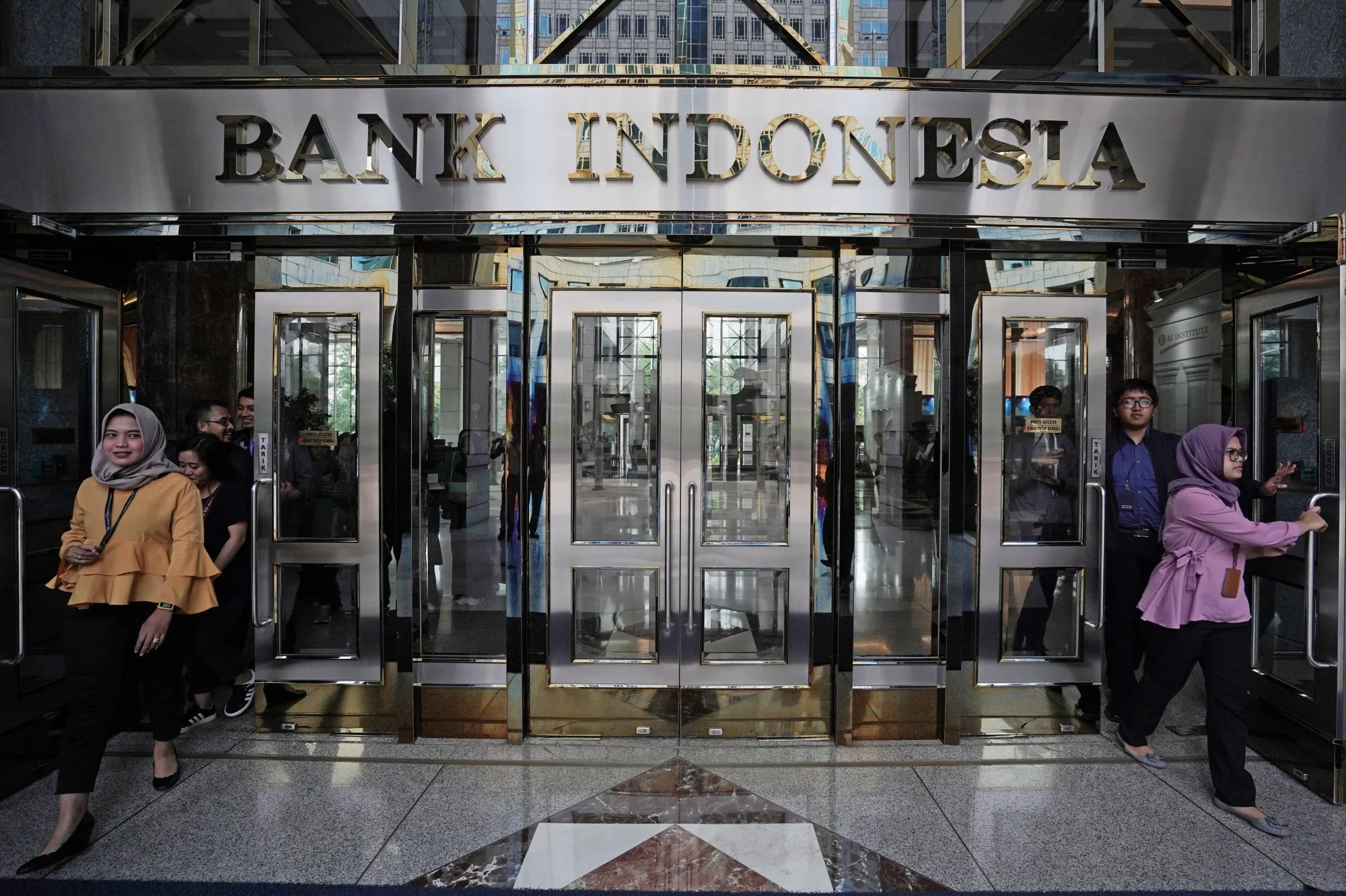 People exit the Bank Indonesia headquarters in Jakarta, Indonesia.