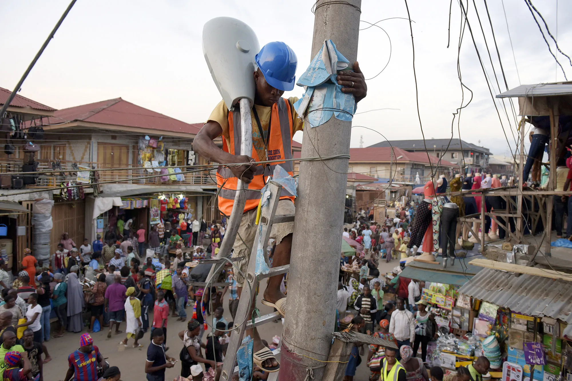 A worker sets up street lamp in the market area of the Oshodi district in Lagos.&nbsp;